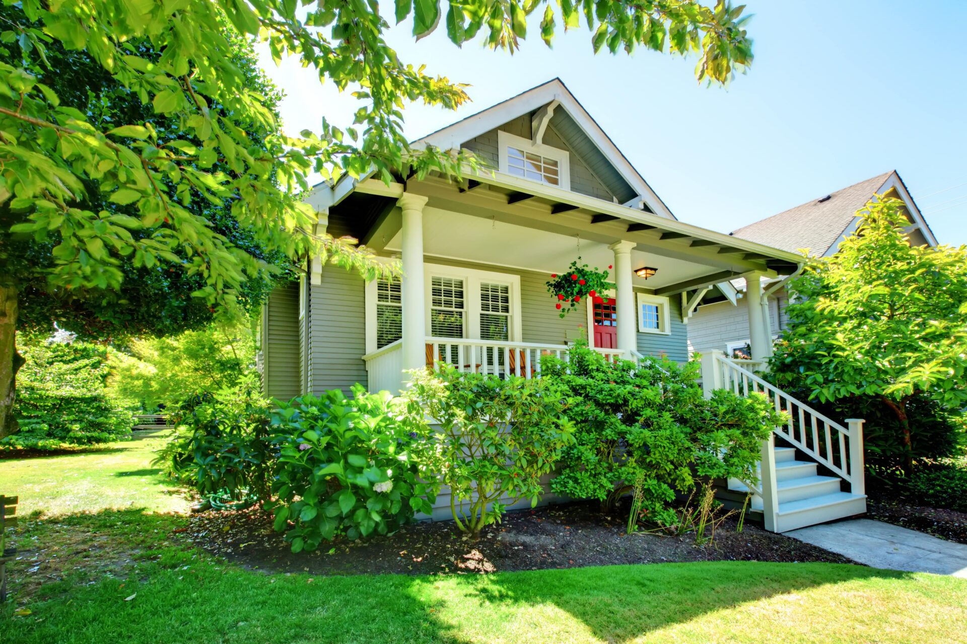 A cozy colonial style home surrounded by green plants